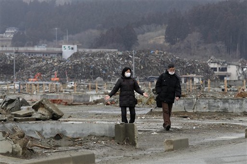 A couple walk in an area devastated by the March 11, 2011 earthquake and tsunami, in Minamisanriku, Miyagi Prefecture om Sunday, March 11, 2012. Japan was remembering the terrifying earthquake and tsunami that struck the nation a year ago on Sunday, killing just over 19,000 people and unleashing the world's worst nuclear crisis in a quarter century. (AP Photo/Shizuo Kambayashi)