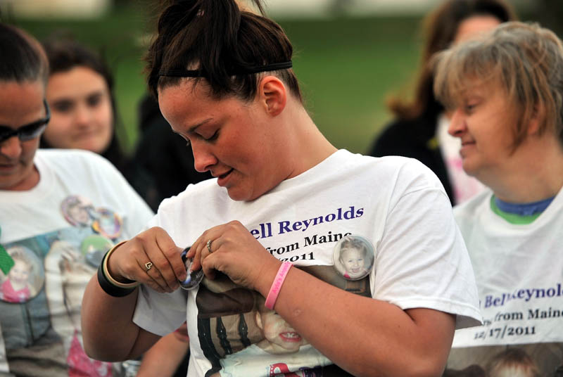 Ashley Pouliot, center, pins a a button with missing toddler Ayla Reynolds picture on to her Ayla Reynolds t-shirt before a vigil at the Church of God on Upper Main Street in Waterville Thursday. Cameras were not allowed in to the church to photograph the actual vigil.