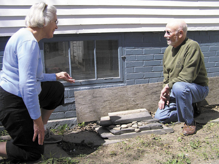 ENTRY POINT: State Rep. Thomas Longstaff and his wife, Cindy, on Thursday inspect the cellar window where a burglar gained entry to their house the previous day. Cindy Longstaff chased the woman burglar down the street, grabbed the computer she had stolen from her husband’s office, and told her to stay put until police arrived.