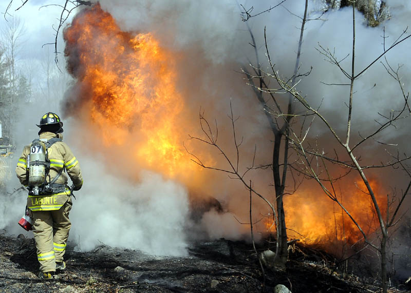 A firefighter approaches a burning fuel storage tank Tuesday after it exploded in Manchester, injuring Edward Bishop of Oakland. Bishop, who suffered serious burns, was listed in fair condition Wednesday at Maine Medical Center in Portland.