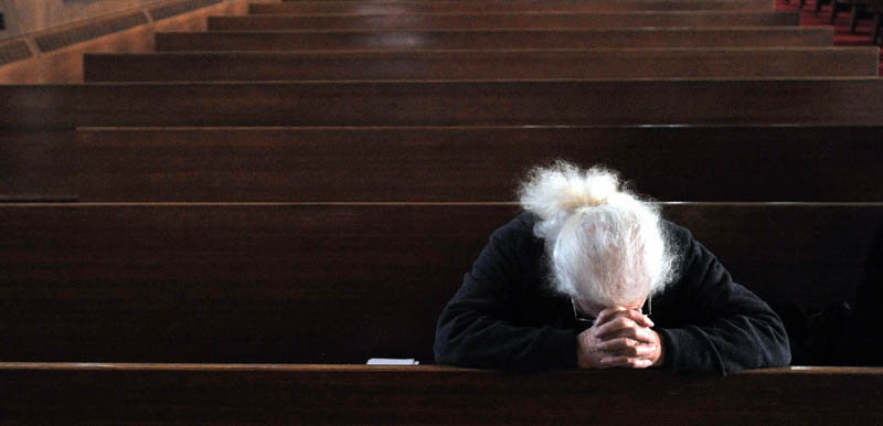 Staff Photo by Michael G. Seamans Shyla Spear prays duringGood Friday Mass at Sacred Heart Church in Waterville. The Holy Trinity Anglican Church rents space at Sacred Heart Church.