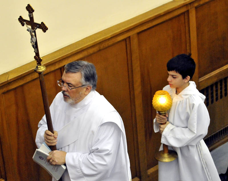 Staff Photo by Michael G. Seamans Sub-deacon Stephen Crate and altar server Benjamin Hodgkin lead the procession during the Holy Thursday service at St. Joseph's Maronite Church in Waterville Thursday evening. In the Holy Thursday service, Father Larry Jensen washed the feet of some parishiners as did Jesus and his disciples before the Last Supper.