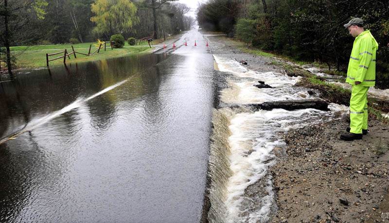 Tom Nadeau, Belgrade grounds facilitator, examines a washed-out section of the Castle Island Road in Belgrade on Monday. Heavy rains flooded a nearby culvert and runoff water undercut the now-closed state roadway.