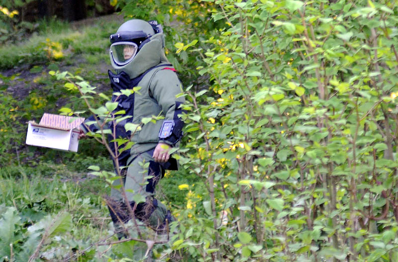 Maine State Police Sgt. Jeff Mills carries material to detonate Thursday outside an apartment building on Gage Street in Augusta. Law enforcement officers from several agencies searched two apartment buildings on the street for explosive materials. The State Police Bombs Team exploded material located in an apartment on Gage Street in the yard behind behind it.