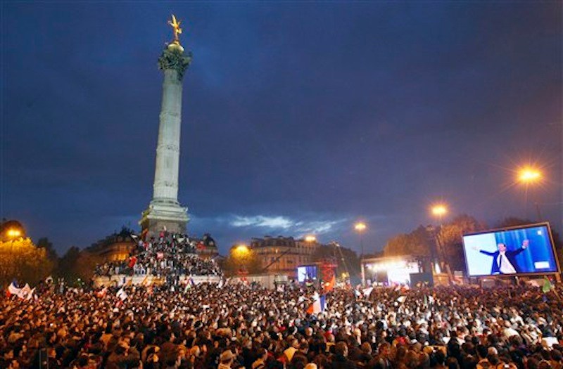 Supporters of Socialist President-elect Francois Hollande, seen on the video screen at right, celebrate after the results of the second round of the French Presidential elections were announced at Bastille square in Paris, France, Sunday, May 6, 2012. Hollande defeated outgoing President Nicolas Sarkozy on Sunday to become France's next president, Sarkozy conceded defeat minutes after the polls closed. (AP Photo/Francois Mori)