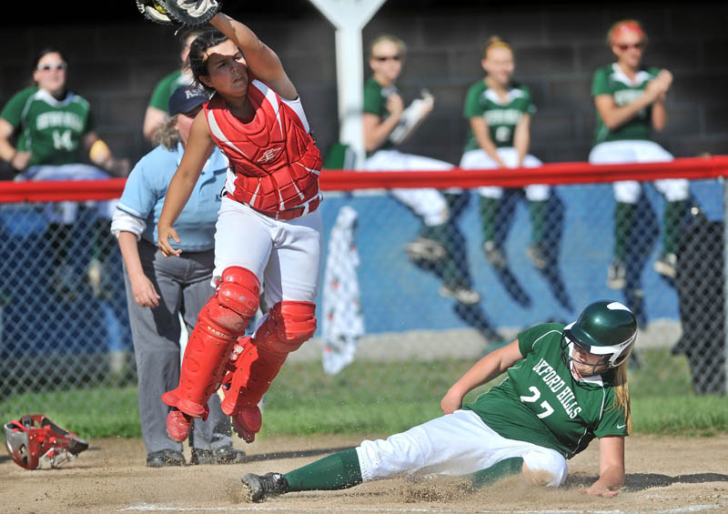 Staff Photo by Michael G. Seamans Messalonskee High School catcher Natalie Hunt, 16, jumps for the ball as Oxford Hills High School's Jordyn Sawborn, 27, slides safely across home plate at Messalonskee High School in Oakland Wednesday.