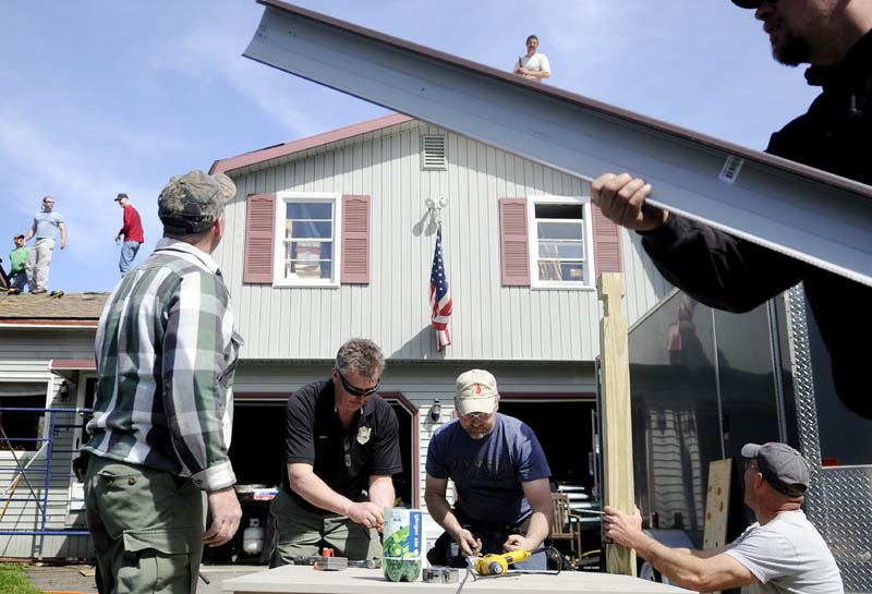 Game wardens and friends of Warden Service Maj. Gregg Sanborn put a new roof on his Sidney home Monday afternoon. Sanborn, who is afflicted with cancer, said about 25 of his colleagues and friends simply “saw a need and acted” to help him. Volunteers stripped, wrapped and shingled 2,700 square feet on the home.
