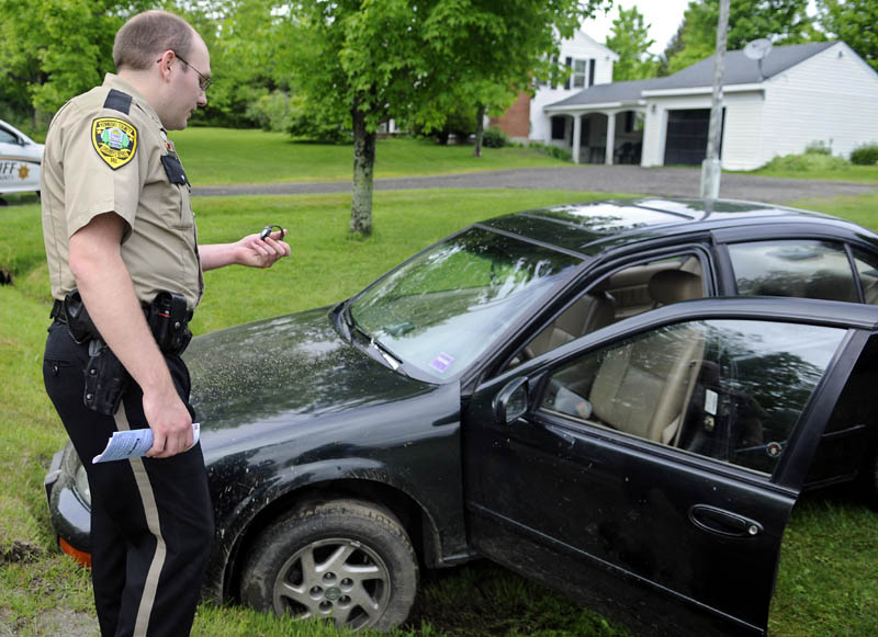 Kennebec County Deputy Nathan McNally inspects his wrist watch Tuesday after it was retrieved from a vehicle that dragged him following a traffic stop in Belgrade. McNally attempted to arrest Angie Soucy when she allegedly drove off with his hand stuck in her vehicle, according to police. McNally was uninjured.