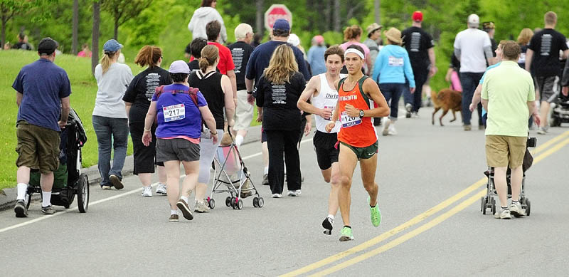 Runners Luke Fontaine, right, has an early lead on Andy Spaulding as they run back through walkers on a looping section of the Mile for Mills 5k on Monday morning at Cony High School in Augusta. Fontaine, 20 of Augusta, stayed in the lead and won with a time of 15:45.68 ahead of Spaulding, 41, of Freeport, at 15:54.33. Almost 400 runners raised over $13,000 for the family of Army Staff Sgt. Travis Mills who lost all four limbs when he was wounded while serving in Afghanistan.