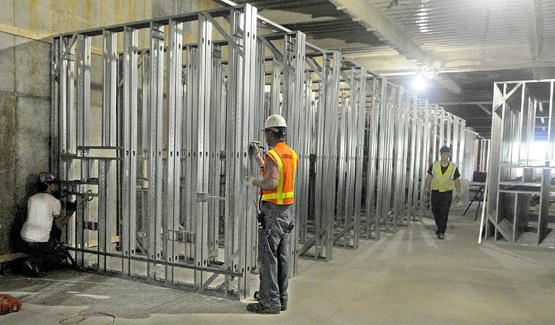 Workers are prefabricating the walls behind patient beds with wiring and piping before they're installed upstairs at MaineGeneral's new regional hospital under construction in North Augusta.