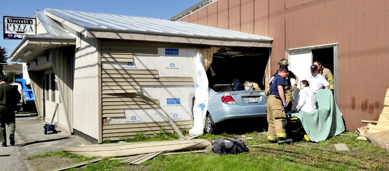 INJURY: Driver Sharon Roderick of Fairfield is treated on a gurney after being removed from her vehicle that crashed through a wall and into the Darrell's Pizza building in Waterville on Monday.