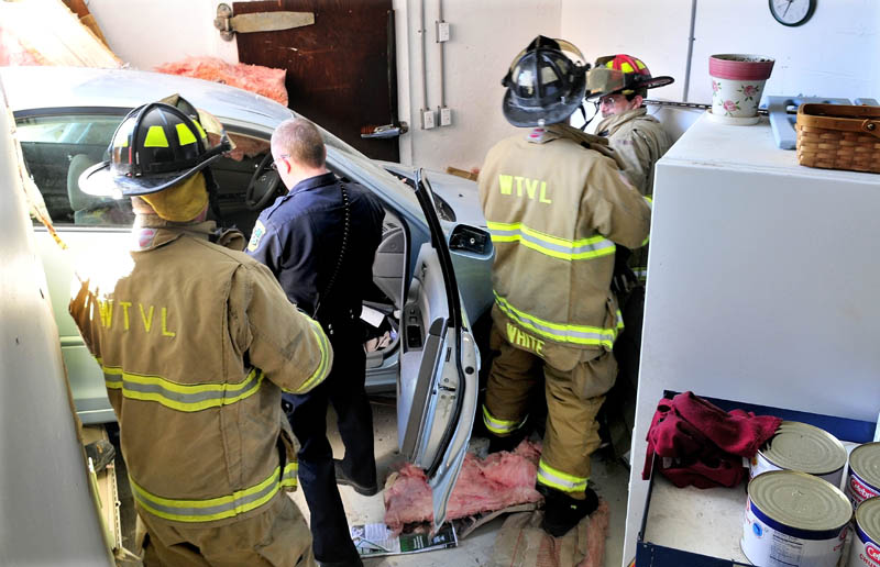 COLLEGE AVENUE CRASH: Waterville police officer Adam Sirois and firefighters work around the vehicle that crashed into Darrell’s Pizza in Waterville on Monday. The driver, Sharon Roderick of Fairfield, was hospitalized with undisclosed injuries. No one else was hurt.