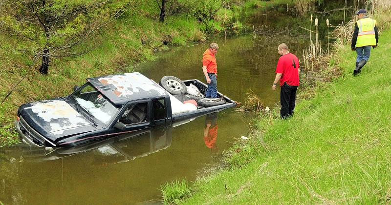 SUBMERGED: Driver Shane Sours, 37, of Starks, stands on shore talking to wrecker operators who are pulling his 1992 Dodge Dakota out of a drainage ditch on Wednesday in West Gardiner. One person suffered minor injuries when the pickup truck skidded off Interstate 95 and ended up partially submerged. Maine State Police Trooper Niles Krech said the crash occurred around 1:45 p.m., when Sours blacked out briefly during a coughing attack while driving on the southbound off ramp at exit 103. The truck hit a guardrail and caromed down an embankment into the ditch. Krech said water flooded the truck to the seats inside the cab.