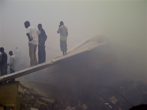 Onlookers stand on the tail wing of a crashed passenger plane in a neighborhood just north of Murtala Muhammed International Airport, in Lagos, Nigeria, today.