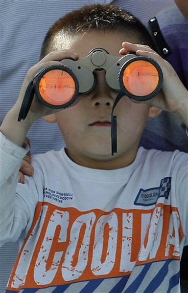 A child uses a pair of binoculars to view the Shenzhou 9 spacecraft rocket before it launches from the Jiuquan Satellite Launch Center in Jiuquan, China, Saturday, June 16, 2012. China sends its first woman and two other astronauts into space Saturday to work on a temporary space station for about a week, in a key step toward becoming only the third nation to set up a permanent base in orbit.(AP Photo/Ng Han Guan)