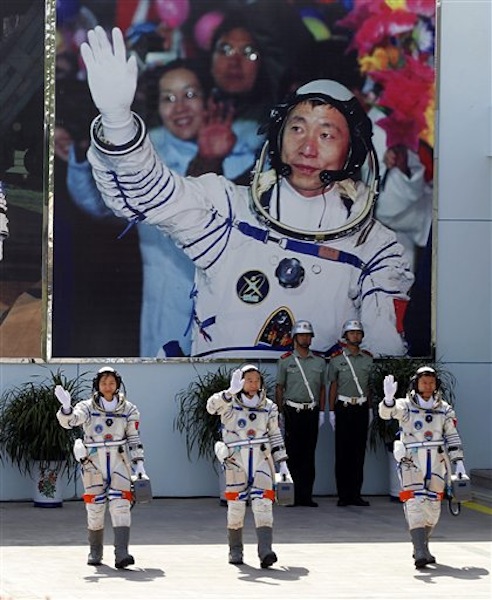 China's astronauts from left., Liu Yang, Jing Haipeng and Liu Wang wave and walk before a giant portrait of China's first astronaut Yang Liwei, as they depart for the Shenzhou 9 spacecraft rocket launch pad at the Jiuquan Satellite Launch Center in Jiuquan, China, Saturday, June 16, 2012. China will send its first woman and two other astronauts into space Saturday to work on a temporary space station for about a week, in a key step toward becoming only the third nation to set up a permanent base in orbit. (AP Photo/Ng Han Guan)