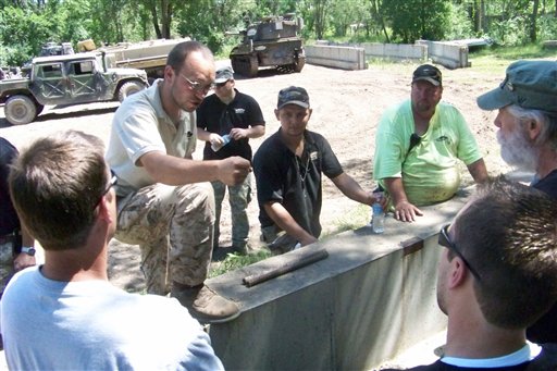 Drive-A-Tank owner and president Tony Borglum, left, gives participants a lesson in driving a tank. For a fee, Drive-A-Tank gives people a chance to drive a tank around a mile-long dirt course and to crush a car with a tank.