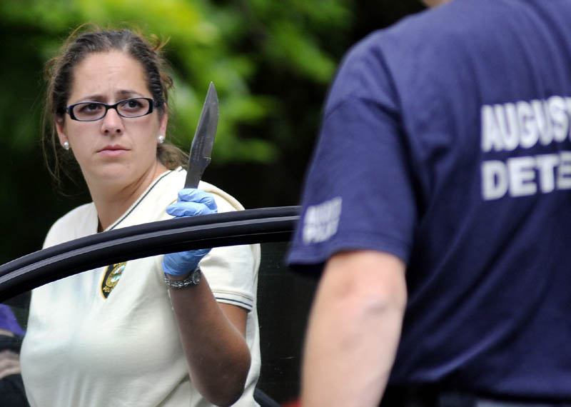 Augusta Police Dept. Detective Tori Tracy holds a knife recovered from a vehicle she searched Tuesday with Det. Sgt. Matt Clark at 21 Glenwood Street in Augusta. Jennifer Dowling and Michael Pierce were arrested after drug agents and police agents executed a search warrant at the home.