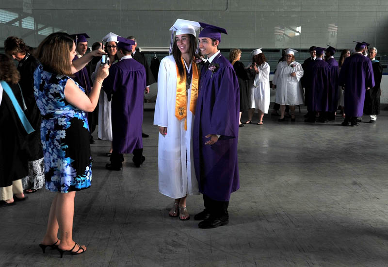 Staff Photo by Michael G. Seamans Waterville Senior High School 2012 class advisor. Heather Duquette, left, snaps pictures of her students back stage prior to commencement ceremonies at Wadsworth Gymnasium at Colby College in Waterville Thursday.