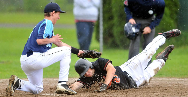 Staff Photo by Michael G. Seamans Winslow High School's Donnie Camp, 27, slides safely iacross home plate under the tag from Oceanside High School pitcher Nick Judge, 1, after a wild pitch in the third inning in the Eastern Class B preliminary game in Winslow.