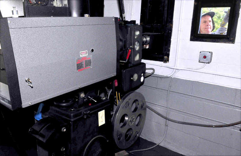 NOW SHOWING: Skowhegan Drive-In owner Donald Brown Jr. is seen working outside on a projection room window beside one of the two reel projectors on Friday.