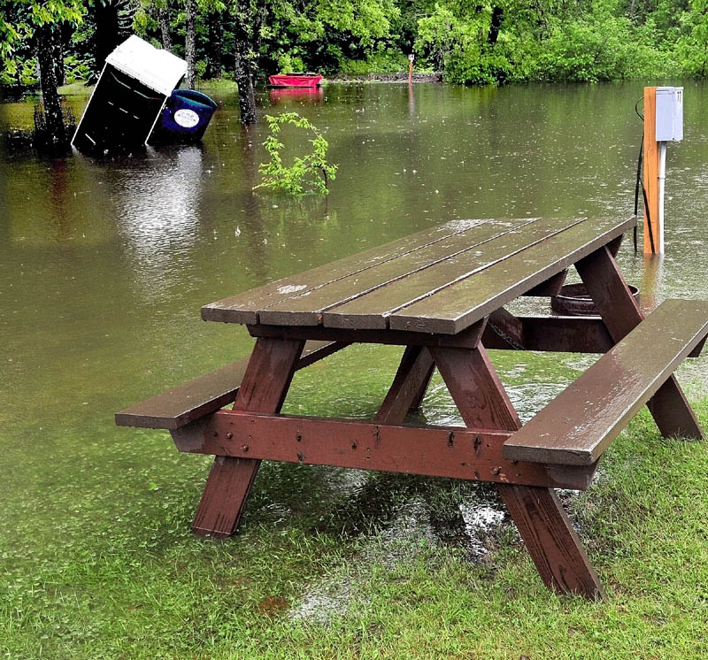 INVASIVE WATER: High water from the nearby rising Kennebec River flooded parts of lawn filled with picnic tables and flooded and toppled an outdoor portable toilet at the Two Rivers Campground in Skowhegan on Monday.