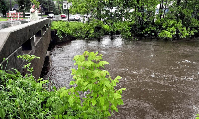 HIGH WATER: William Dawe of Canaan photographs the high water that flowed in Beaver Brook in Clinton on Monday. Officials closed the bridge and another one on the nearby Hinckley Road to traffic as water approached the roadways.