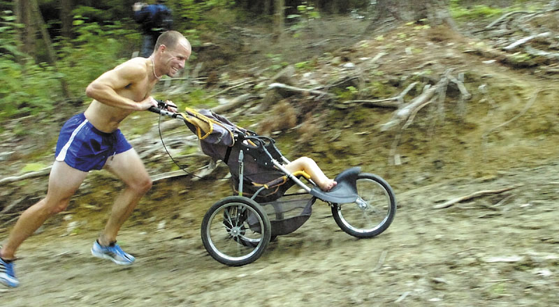 Staff photo by Joe Phelan Wade Boudrea, 35 of Wintrhop, pushes is 19-month-old daughter Scout around the course on Thursday night in the Bond Brook Recreation Area in Augusta. There were 29 finishers, not counting Scout, in the race. There will be four more races in the series on Thursday evenings at six through Sept. 15. Check augustatrails.com for more information.