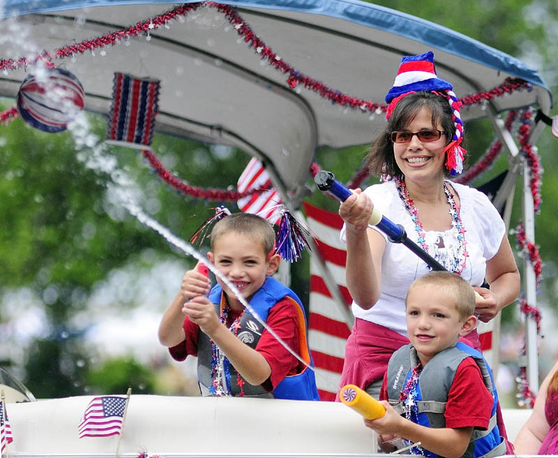 Boaters spray water on spectators during a boat parade on Mill Stream Wednesday in Belgrade Lakes village.