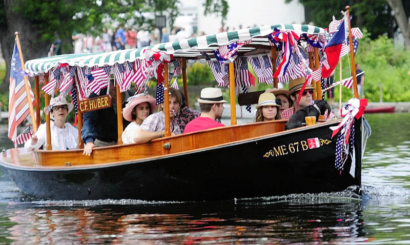 A boat parades down Mill Stream on Wednesday in Belgrade Lakes village.