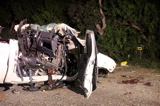 The wreckage of a pickup truck that authorities say was overloaded with passengers when it veered off a highway and crashed into trees near Goliad, Texas.