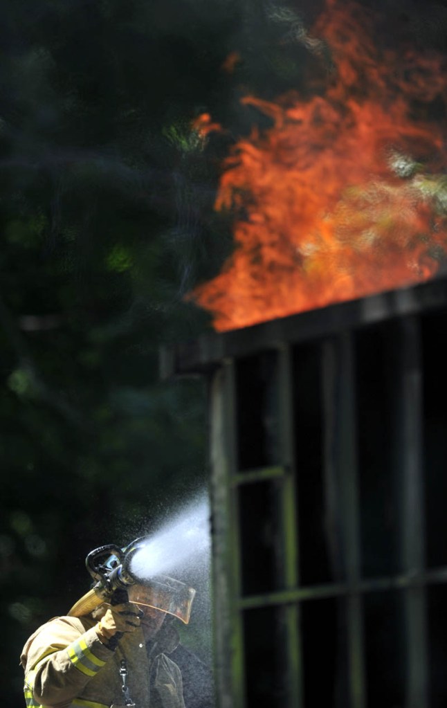 A firefighter from Winslow Fire Department battle a dumpster fire on Barton Street Wednesday in Winslow. The fire apparently started when a construction worker discarded a cigarette in the dumpster.