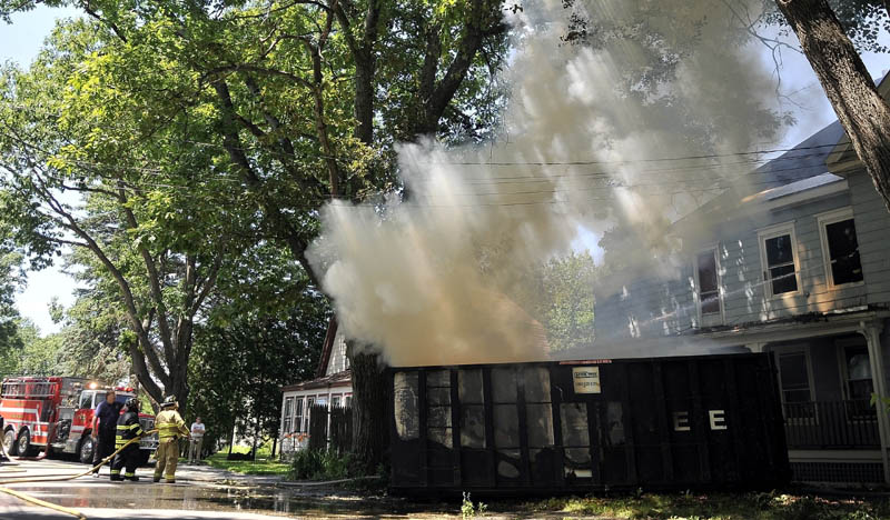 A firefighters from Winslow Fire Department battle a dumpster fire on Barton Street in Winslow Wednesday. The fire apparently started when a construction worker discarded a cigarette in the dumpster.