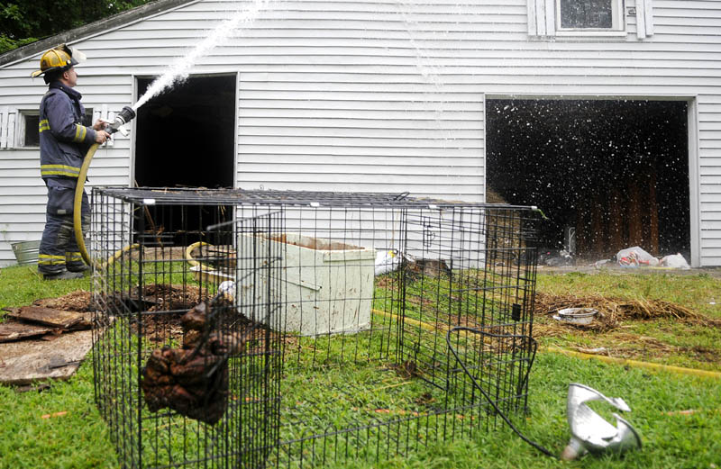 KNOCK DOWN: Farmingdale firefighter Julian Beale extinguishes a hot spot Thursday on a barn that caught fire at a Farmingdale residence when a heat lamp, at right, erupted. No injuries were reported, according to firefighters.