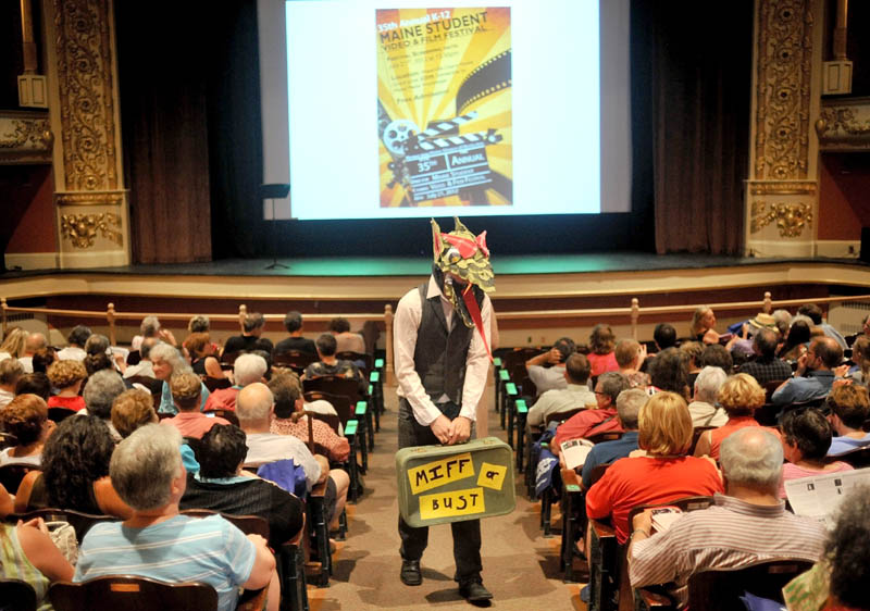 Sam Ranger, center, roams the aisles at the Waterville Opera House as the Maine International Film Festival mascott Dragon as film goers take their seats before the showing of Vacationland on Friday.