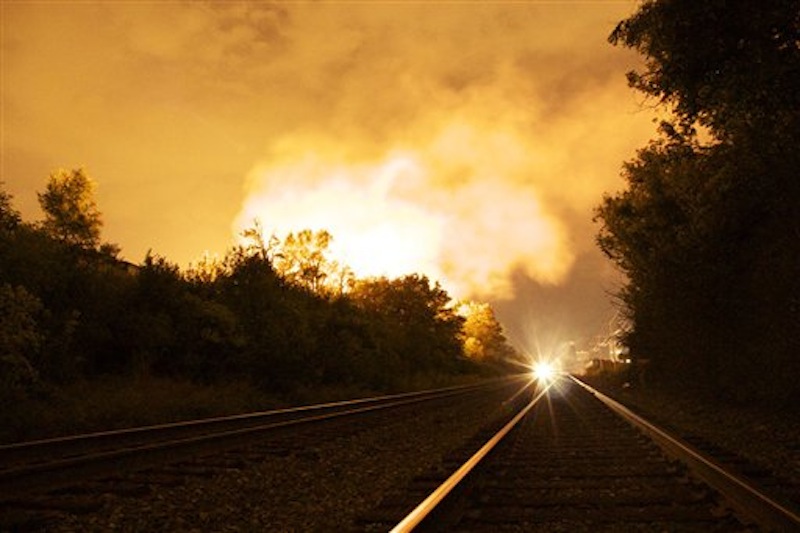 Flames rise from a derailed freight train, left unseen, early Wednesday July 11, 2012 in Columbus Ohio. Part of a freight train derailed and caught fire in Ohio's capital city early Wednesday, shooting flames skyward into the darkness and prompting the evacuation of a mile-wide area as firefighters and hazardous materials crews worked to determine what was burning and contain the blaze.(AP Photo/Chris Mumma)