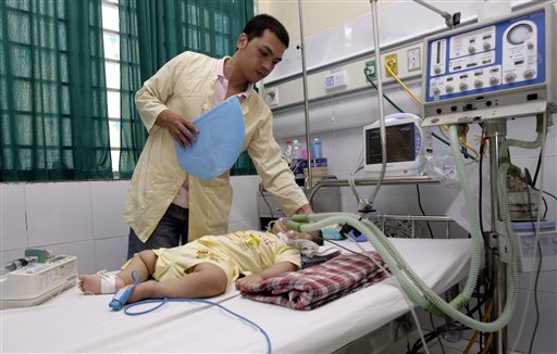 Tran Nam Trung fans his 20-month-old son Tran Minh Giang who has been hospitalized for the past seven months at the National Hospital of Pediatrics.