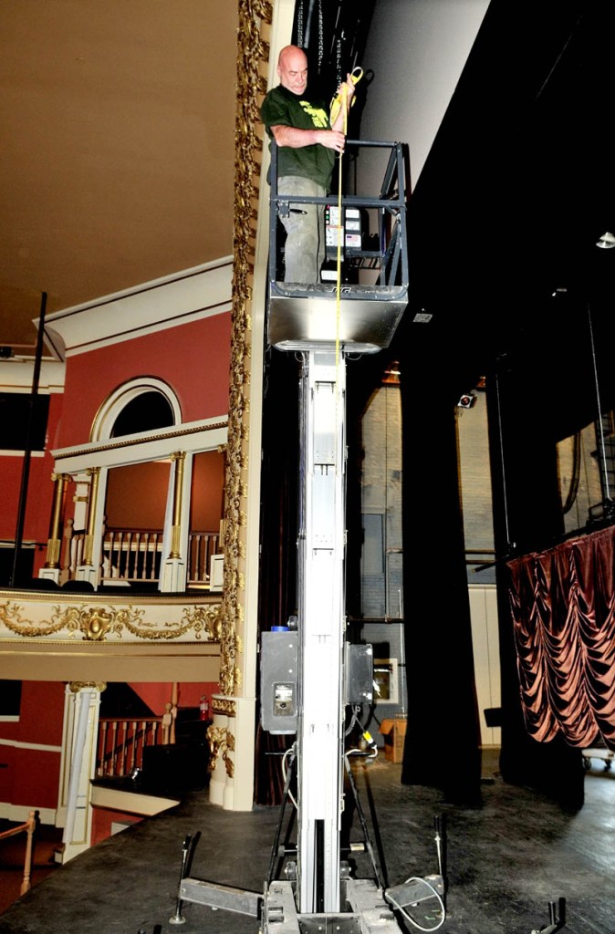 Mike Martineau takes measurements before hanging a stage curtain at the Waterville opera House on Thursday for the Maine International Film Festival.