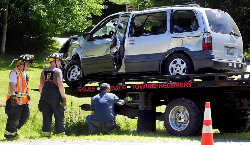 Firefighters talk to a tow truck operator as he loads up a van involved in a two-vehicle crash at the corner of U.S. Route 202 and Bog Road this afternoon in Monmouth.