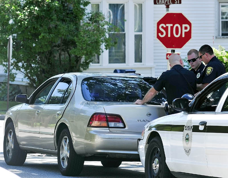 Augusta police officers stand beside a Nissan Maxima with New York plates that they stopped on Green Street near the corner of Chapel Street on Wednesday morning. Two out-of-staters were arrested on gun charges and criminal threatening.