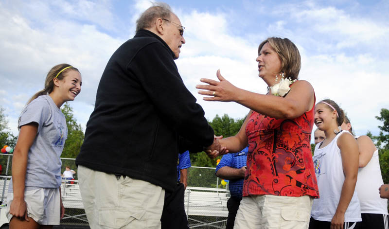 GOOD LUCK: Cony High School girls soccer team honorary captain Bill Ottman, left, and Gardiner Area High School honorary captain Nancy Hicks great each other Monday before the coin toss before the Drive Out Cancer Challenge game to raise funds for cancer research in Gardiner.