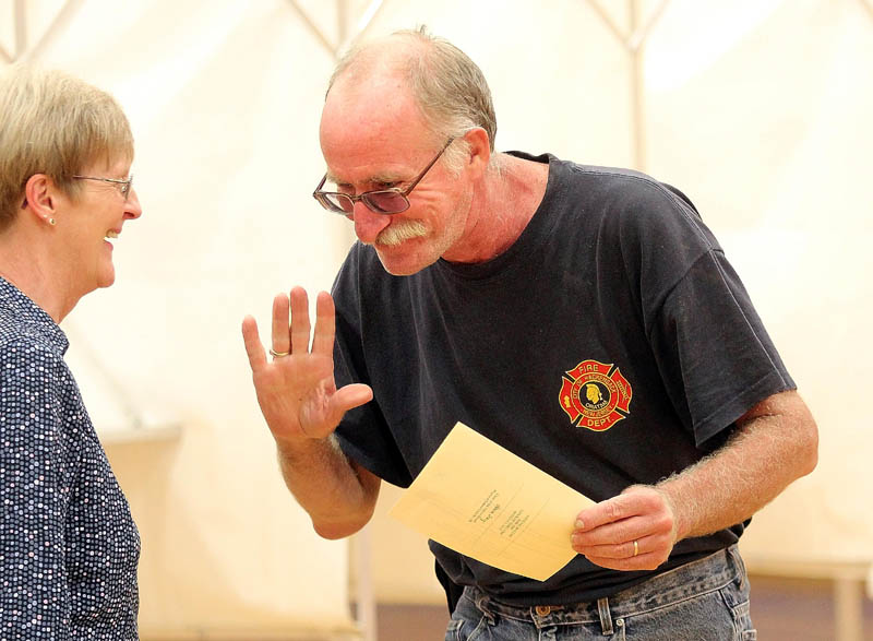 CASTING HIS VOTE: Gerald Roderick chats briefly with Oakland Town Clerk Janice Porter after voting on the latest version of the Regional School Unit 18 budget on Tuesday.