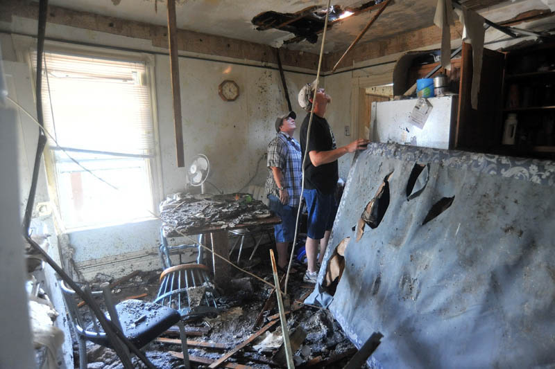 Heidi Nickerson, left, and Jeff White, right, look through a hole in the ceiling in the second floor apartment of Nickerson's mother-in-law Pam LaBrie, on Spruce Street in Waterville on Thursday.