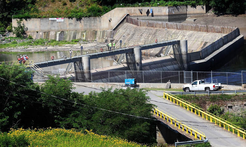 Workers stand atop the Brookfield Dam, which spans the Kennebec River between Winslow and Waterville, on Tuesday. The water level of the Kennebec River has been lowered for dam maintenance.