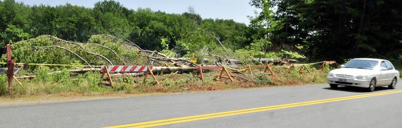 A motorist drives on Whittier Road in Farmington in July past an area where trees have been felled to help slow river bank erosion beside the Sandy River, which flows in background. DeadRiver made the decision to keep its trucks off the road because of safety concerns.