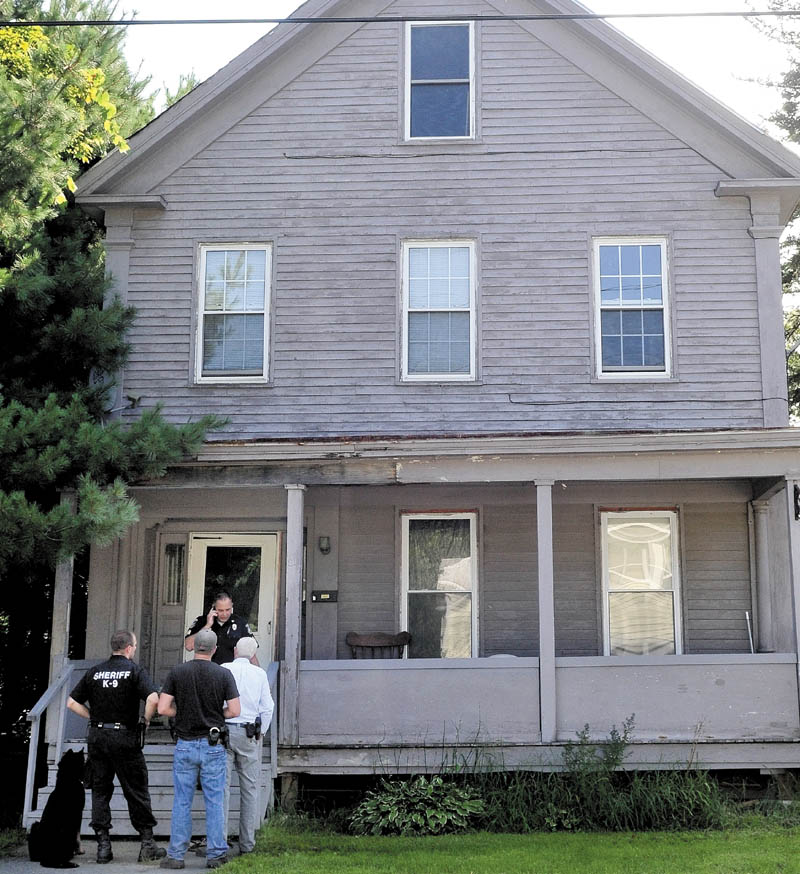 Police talk outside a home on Pleasant Street in Waterville after two men were arrested in connection with a drug robbery on Tuesday.