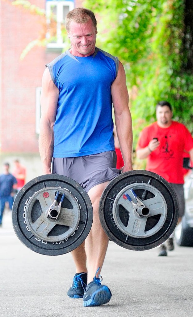 CARRIER: Jason Fish walks with a heavy load in each hand in the farmer's carry event during the Downtown Throwdown strongman contest on Front Street Saturday morning in downtown Augusta.