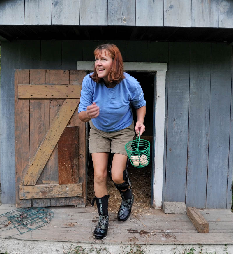 CHICKENS: Jean Rosborough emerges from one of her chicken coops with fresh eggs at her home on U.S. Route 201 in Vassalboro on Saturday morning. Waterville city councilors on Tuesday are scheduled to consider allowing people in certain parts of the city to have up to six laying hens, under specific conditions, on their properties.