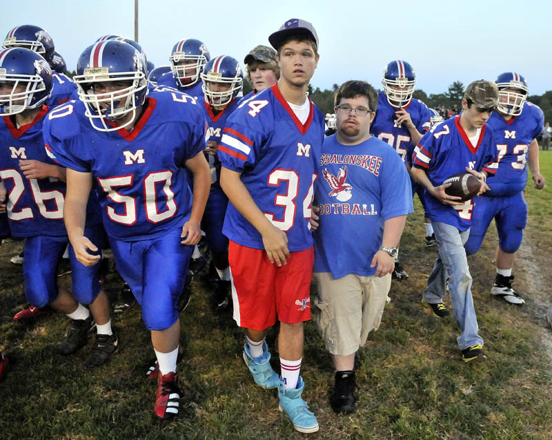 Trevor Perry, middle right, stands with the Messalonskee football team on the center of the field before hosting Skowhegan Area High School in Oakland friday night.