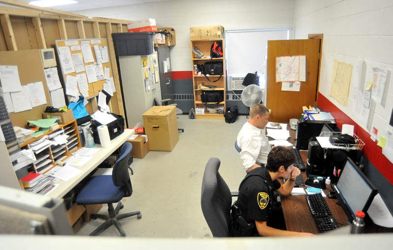 Officer Linda Smedberg, bottom right, and Officer Brandon Lund, upper right, work in the booking room Friday at the temporary Winslow police station in the Winslow Fire Department building on Benton Avenue.